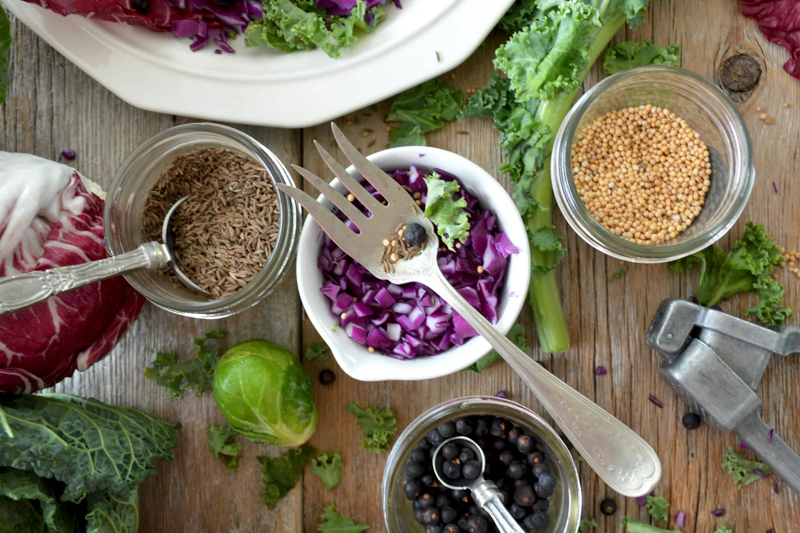 Fresh leafy vegetables, cabbage, seeds and prepared salads arranged on a wooden table