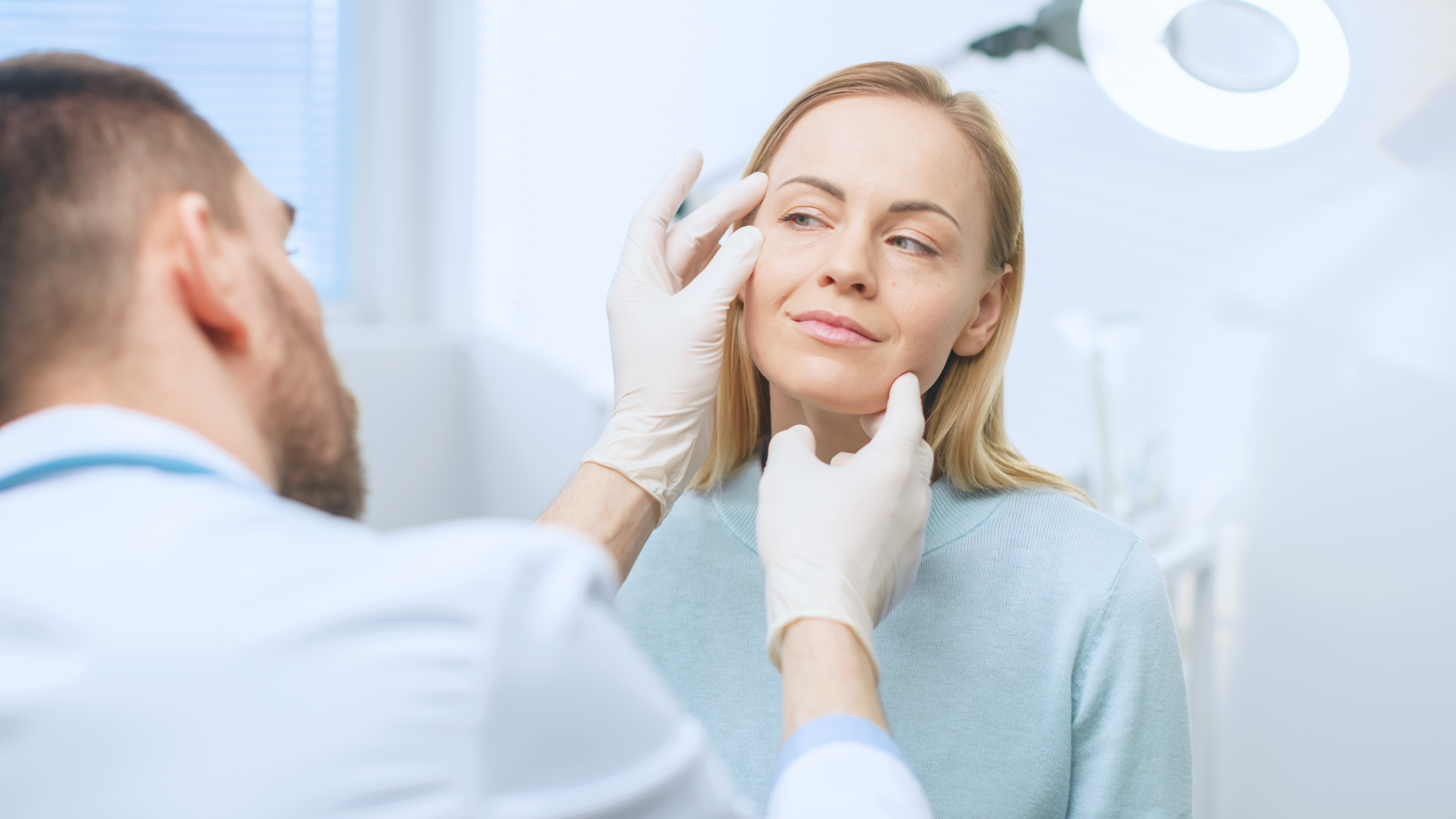 Doctor examining a woman's face during an aesthetic consultation — understanding structural and functional facial aging